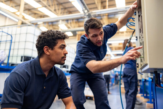 photo - Working engineers operating machines at manufacturing factory