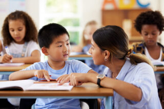 photo - Teacher Helping Student at His Desk in Elementary School Classroom