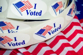 photo - I Voted Sticker Roll Against a US Flag