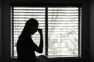photo - Silhouette of Stressed Woman with Bedroom Window in Background