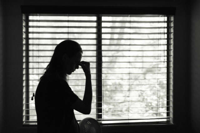 photo - Silhouette of Stressed Woman with Bedroom Window in Background