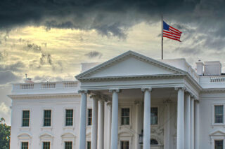 photo - White House with US Flag and Cloudy Sky