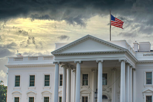 photo - White House with US Flag and Cloudy Sky