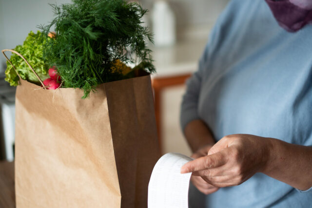 photo - Close Up of Woman in Kitchen Reviewing Grocery Bill