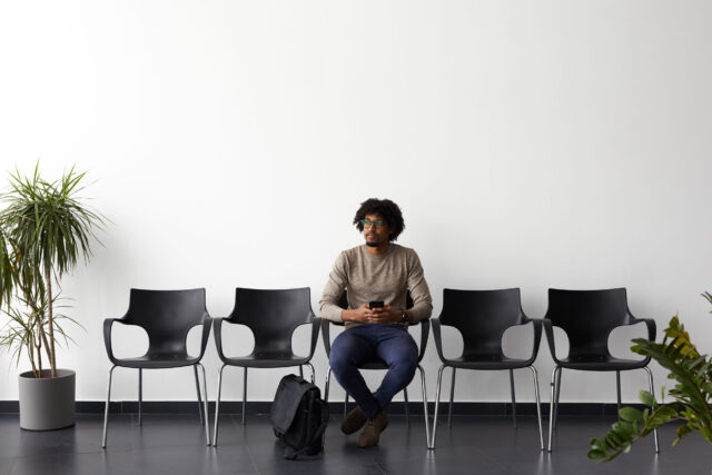 photo - One Man Sitting on a Row of Chairs Awaiting a Job Interview