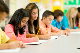 photo - Students Writing with Pencils in a Row in Classroom