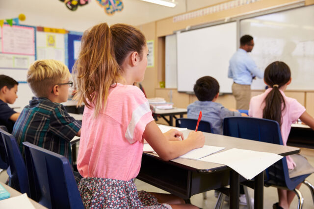 photo - Teacher writing on board in class