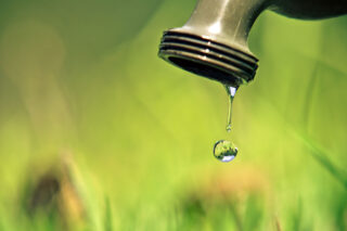 photo - water dripping from faucet with grass background