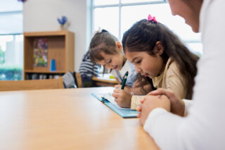 photo- Two Elementary Age Girls Work on Writing Assignment