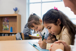 photo - Two Elementary Age Girls Work on Writing Assignment