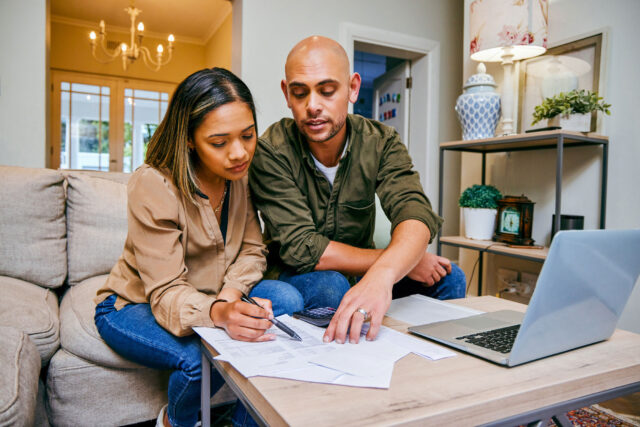 photo - Young Couple Reviewing Their Finances in Livingroom