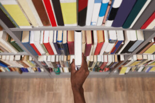 photo - Student Taking Book off Shelf in the Library