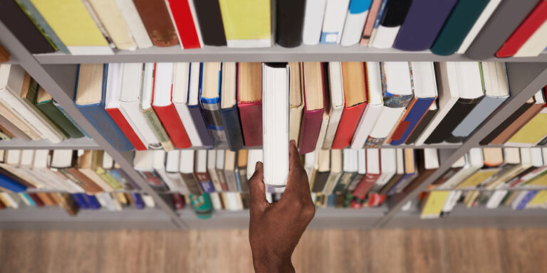 photo - Student Taking Book off Shelf in the Library