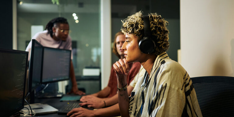 photo - Female Programmer Working on Code in Busy Office with Headphones