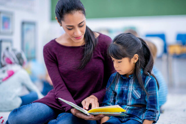 photo - Teacher Reading a Book with a Young Student