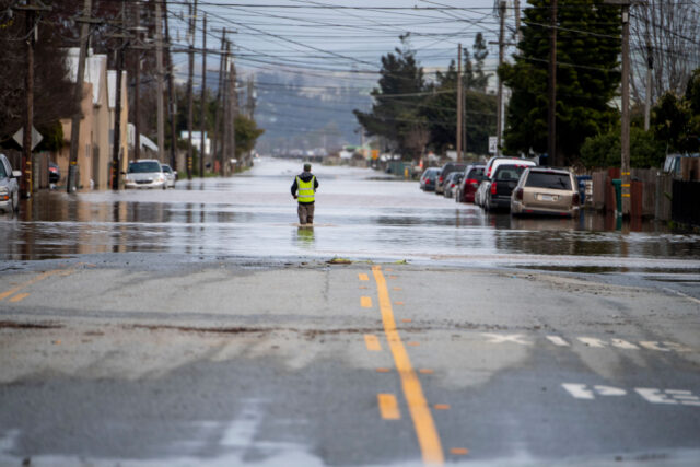 photo- Person Walks through Floodwaters from Levee Breach along the Pajaro River, Monterey County