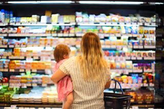photo - Rear View of Mother Holding Baby and Grocery Basket and Shopping in Supermarket