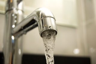 photo - Close up of Water Flowing from Sink Faucet