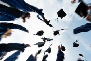 photo - Group of Graduate Students Throwing Graduation Hats to the Sky