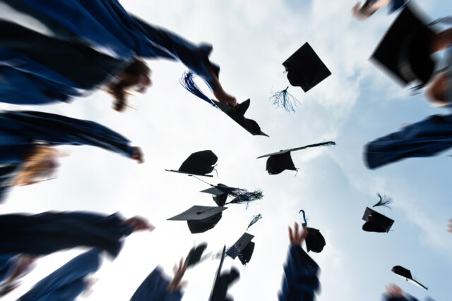 photo - Group of Graduate Students Throwing Graduation Hats to the Sky
