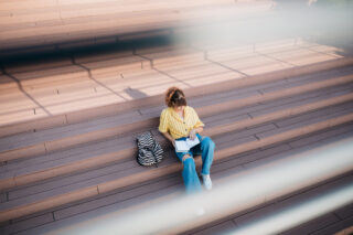 photo - Female Student Reading Book Sitting on Steps