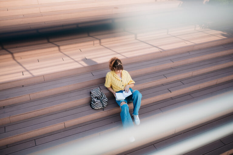 photo - Female Student Reading Book Sitting on Steps