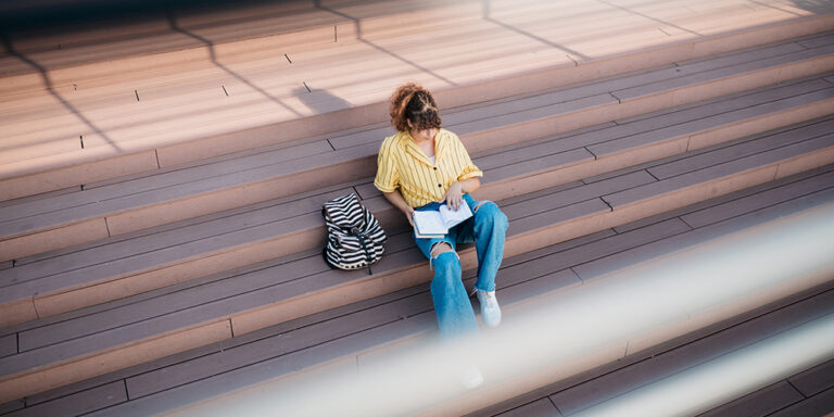 photo - Female Student Reading Book Sitting on Steps