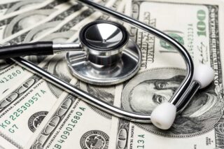 photo - Stethoscope on Top of Hundred Dollar Bills