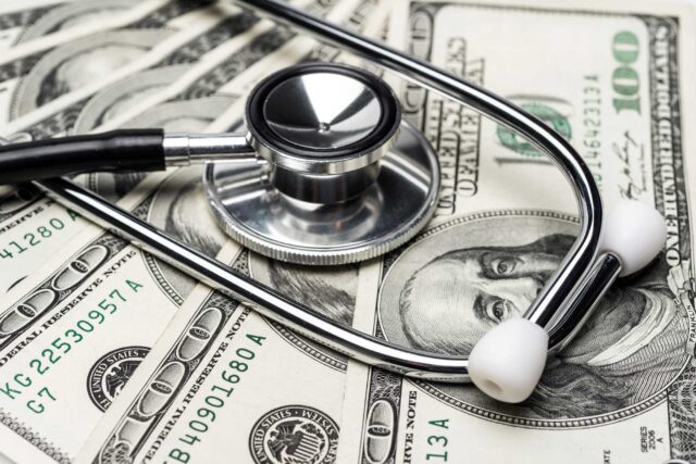 photo - Stethoscope on Top of Hundred Dollar Bills