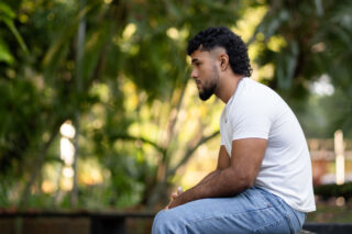 photo - Young Man Sitting in Profile in a Park, Thinking