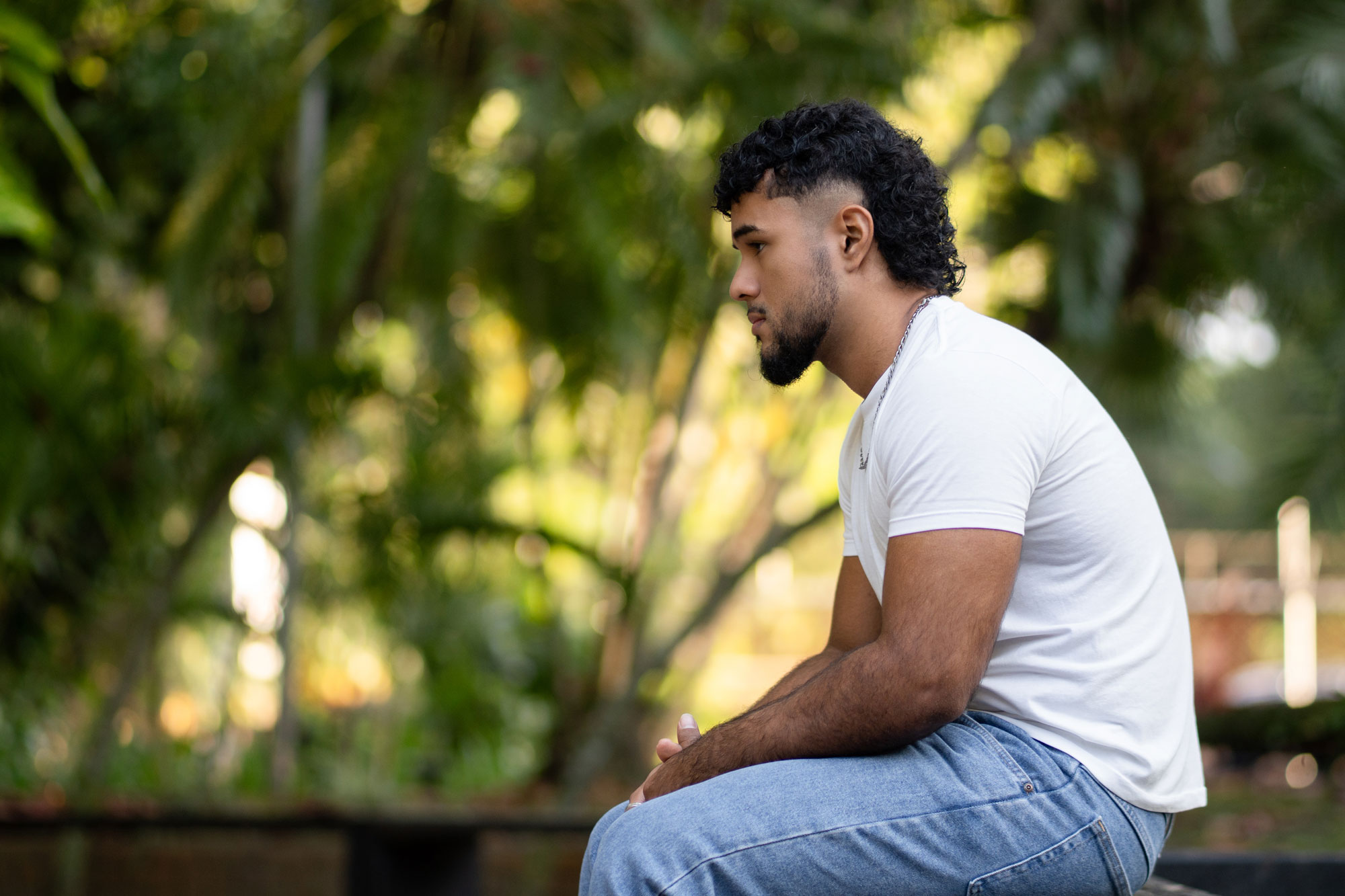photo - Young Man Sitting in Profile in a Park, Thinking