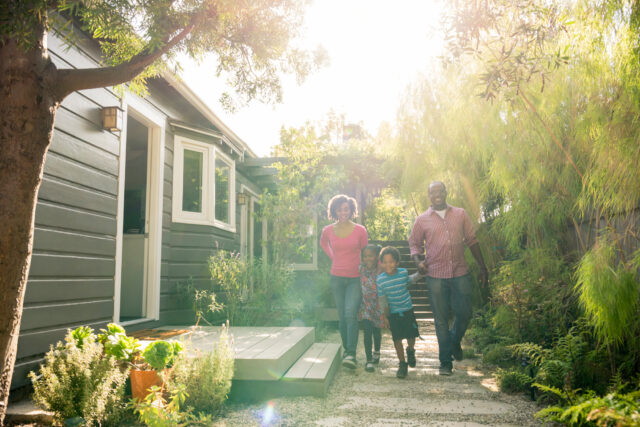photo - African-American Parents with Two Children Walking in Garden