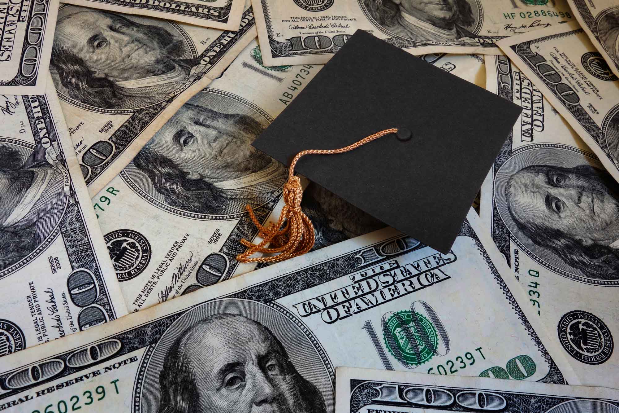 photo - Miniature Graduation Cap on Hundred Dollar Bills