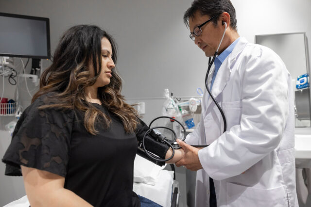 photo - Doctor Taking Patient's Blood Pressure in Exam Room
