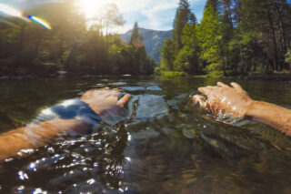 photo - Close Up of Man's Forearms Just under the Water as he Swims in the Merced River in Yosemite