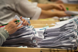 photo - Close Up of Woman Counting Ballots