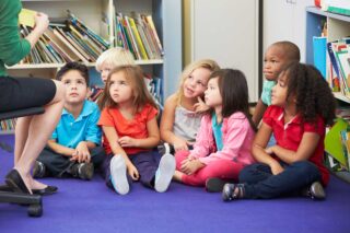 photo - Kindergarteners in Classroom Sitting on Rug and Listening to Their Teacher