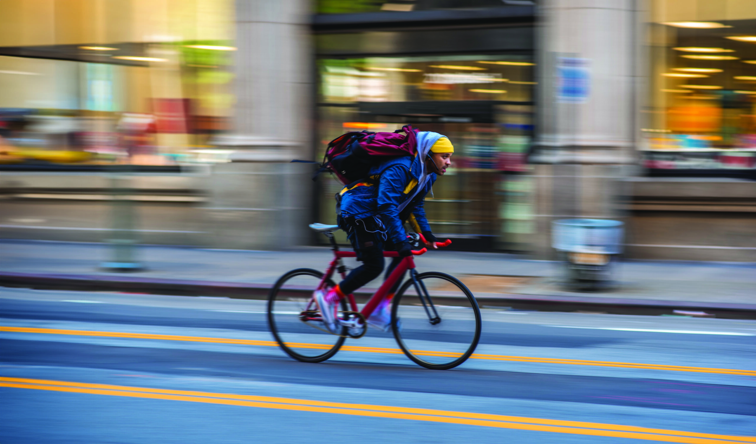 Mixed race bicycle messenger cycling on city street