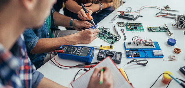 Group of students engineers working on a computer part