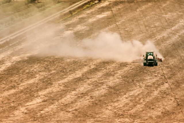 photo - Aerial View of Tractor Kicking Up Dust in Dry Field