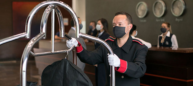photo - Bellboy Working at a Hotel, Wearing a Mask