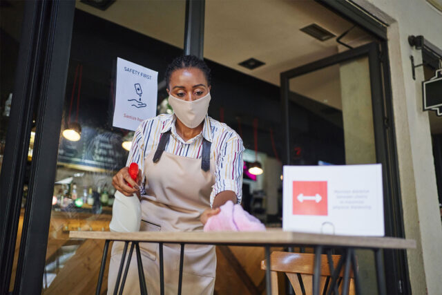 photo - Cafeteria Worker Wearing Mask and Cleaning Outside Table