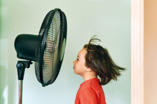 photo - child standing in front of a fan