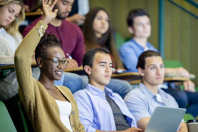 photo - college student raising hand in lecture class