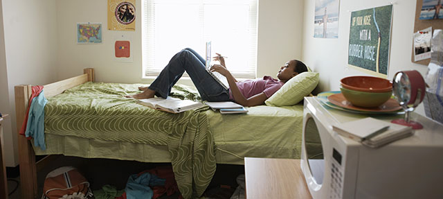 photo - Young Woman Studying on Bed in Dormitory