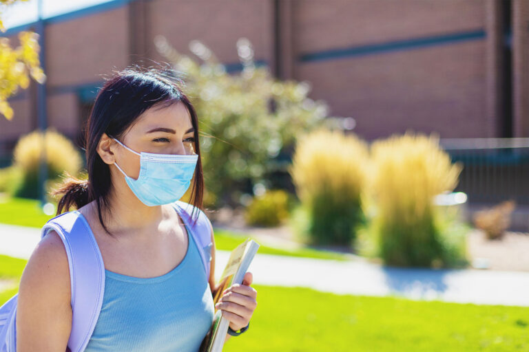 photo - College Student Walking on Campus and Wearing a Mask