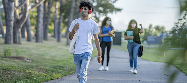 photo - Students Walking on College Campus and Wearing Masks