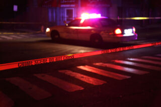 photo - Crime Scene Tape and Police Car at Night