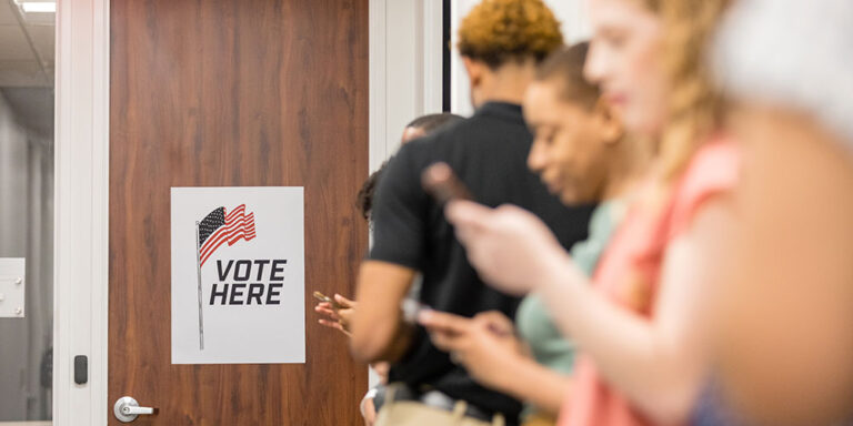 photo - Diverse Group Uses Phones While Waiting To Vote