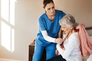 Photo of an elderly woman getting help from a caregiver in a nursing home